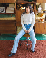 Model sitting on chair wearing the Wanderer Flare in Gracie sustainable denim jeans by Porter Blue Apparel