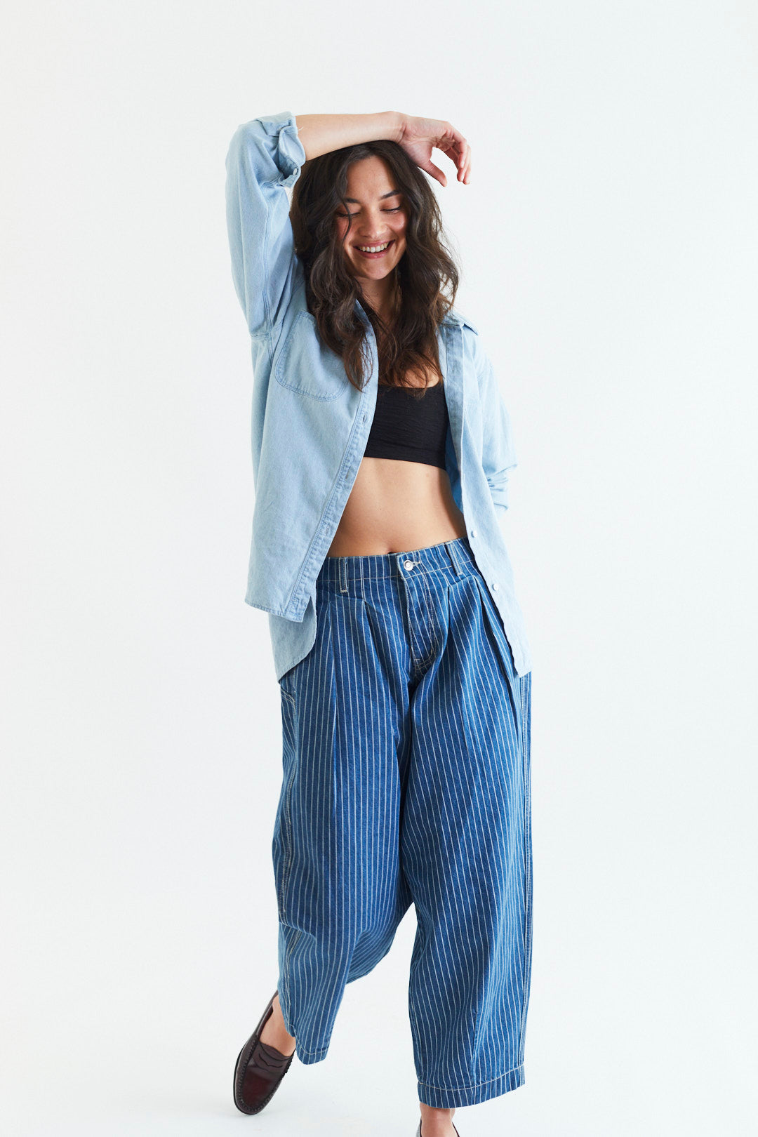 Woman wearing a light blue shirt and blue striped pants on a white background