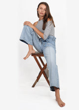 Model sitting in chair wearing the Penny Paperbag Waist Jeans in Eden Wash - Sustainably Made Denim by Porter Blue Apparel
