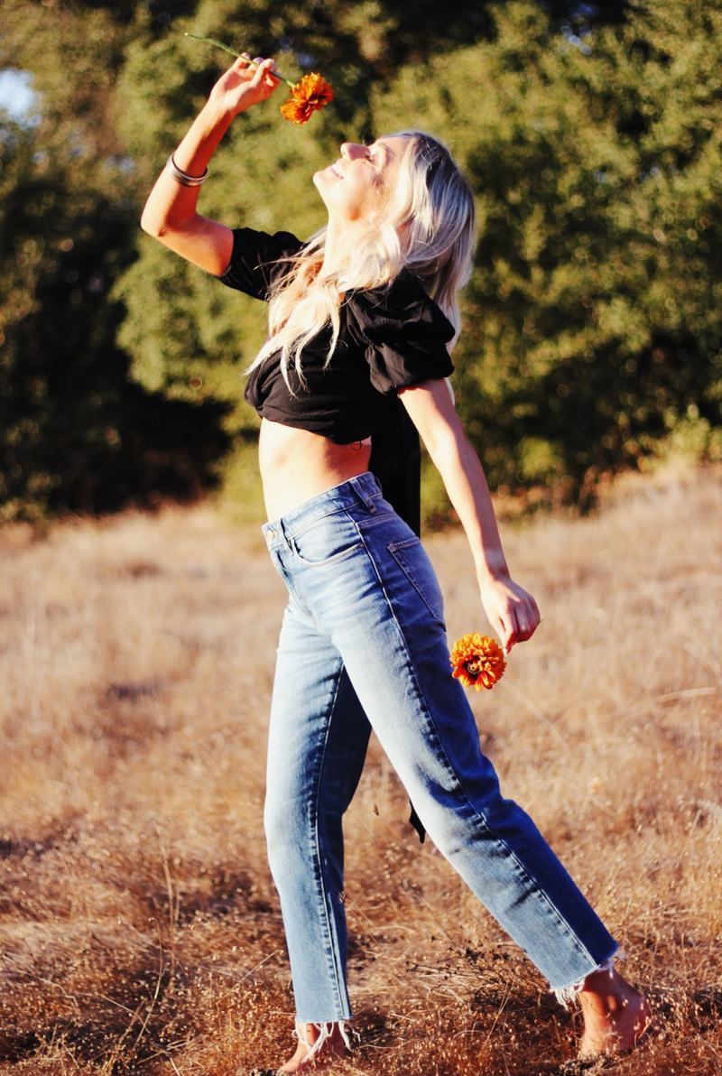 Model smelling a flower wearing Porter Blue Apparel ethically made denim Rebel Straight in Mabel jeans
